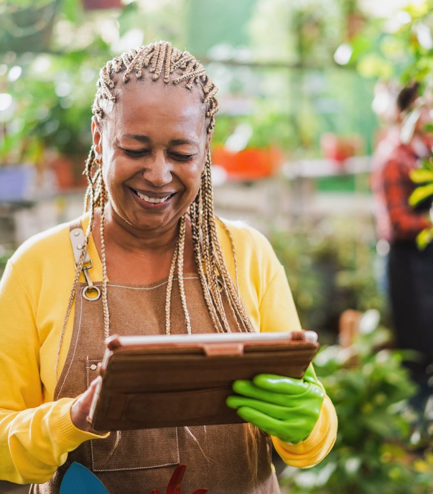 African woman working inside greenhouse garden - Nursery and spring concept - Focus on face